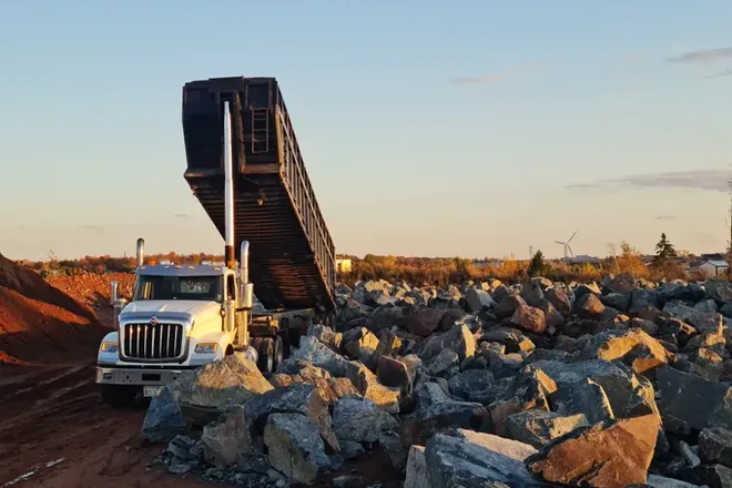 Camion benne déchargeant des blocs sur un chantier