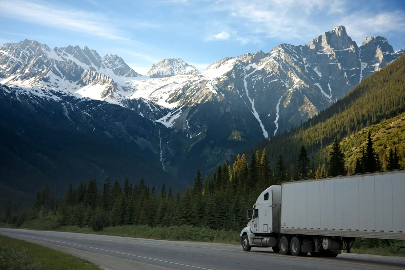 Camion à caisse blanche de type frigorifique roulant sur une route de montagne