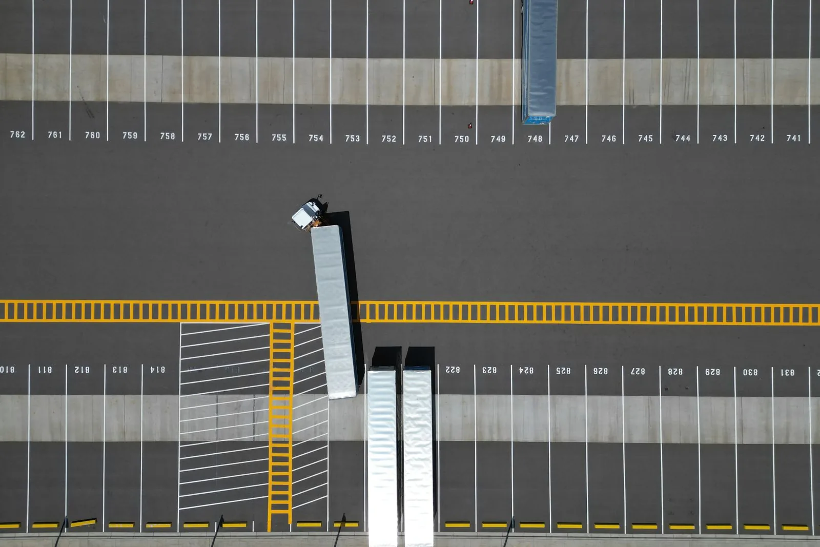 Quai d’un dépôt vu du ciel, une seule remorque stationnée en attente d’un nouveau contrat
